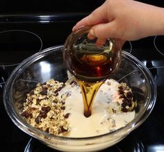 someone is pouring syrup on oatmeal and raisins in a bowl