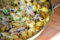 a pot filled with pasta and peas on top of a wooden table