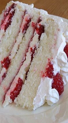 a slice of cake with white frosting and raspberries