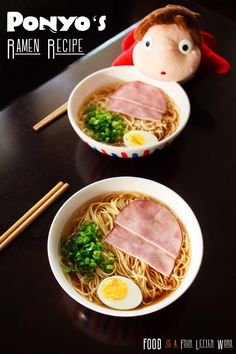 two bowls of ramen with ham and eggs in them on a black table next to chopsticks