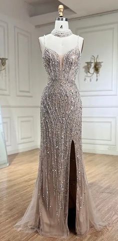 This Sleeveless Sequin and Beaded Embellished Front Slit Gown is a glamorous and eye-catching choice for special occasions. This gown features a sleeveless design that highlights the shoulders and arms, while the bodice is intricately adorned with shimmering sequins and beads, creating a dazzling and luxurious effect. The front slit adds a touch of sophistication and allure, allowing for graceful movement and a hint of drama. Perfect for formal events, galas, or evening parties, this gown combin Sparkle Dress Long, Graceful Movement, Silver Gown, Crystal Dress, Feather Tops, Thousand Oaks, Dream Engagement, Sparkle Dress, Gala Dresses