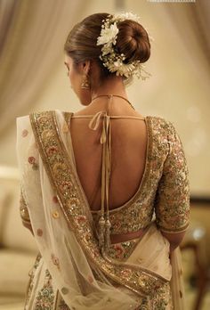 the back of a woman's dress with flowers in her hair and an elaborate headpiece