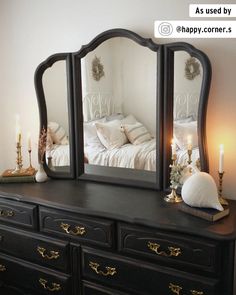 a dresser with two mirrors on top of it and candles in front of the mirror