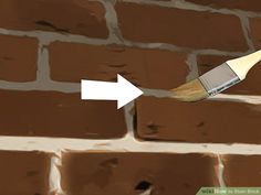 a brick wall with a paint brush sticking out of it's center and an arrow pointing to the right