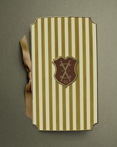 a brown and white striped box with a ribbon around it's edge on a gray surface