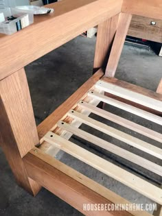 a wooden bed frame sitting on top of a floor next to a desk and chair