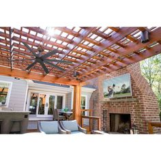 an outdoor living area with a fireplace and ceiling fan