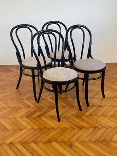 four black chairs sitting on top of a wooden floor