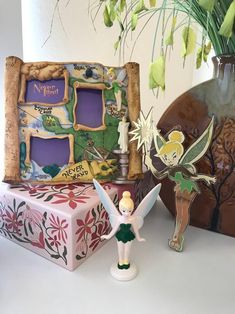 a tinker bell fairy figurine next to a decorative box