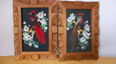 two wooden frames with paintings of birds and flowers in them on a table next to each other