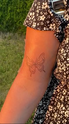 a woman's arm with a tattoo on the side of her left arm and a small butterfly on it