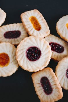 small cookies with jam on them sitting on a black table top next to each other