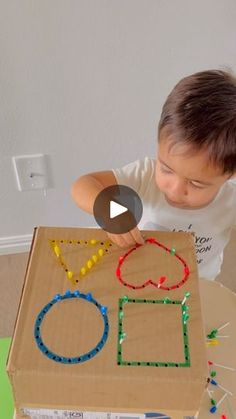 a little boy that is standing in front of a box with some beads on it