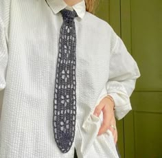 a woman wearing a white shirt and tie holding her hand out to the side while standing in front of a green door