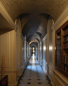 a long hallway with bookshelves and tiled floors