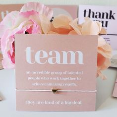 there is a pink card with the words team on it next to flowers and cards