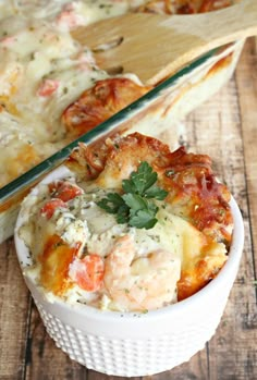 a white bowl filled with shrimp and cheese casserole on top of a wooden table