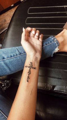 two hands holding each other with a cross tattoo on their wrist and the other arm