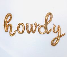 the word chowdy spelled with gold balloons on a white surface, ready to be cut into