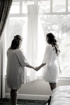 two women standing in front of a window holding hands