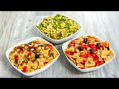 three bowls filled with pasta and vegetables on a wooden table next to a bowl of salad