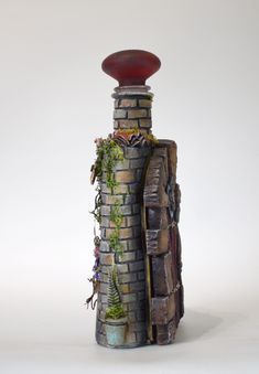 a brick tower with plants growing out of it's sides and a red bowl on top