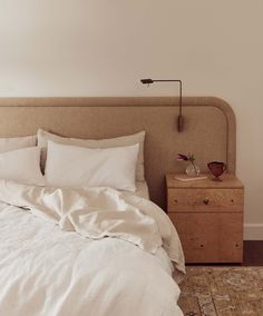 an unmade bed with white linens and pillows on the headboard in a bedroom