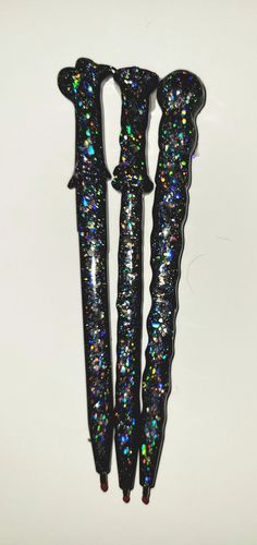 three black and multi - colored glittered toothbrushes on a white surface