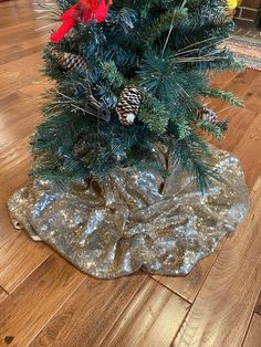 a small christmas tree with pine cones and red flowers in a vase on the floor