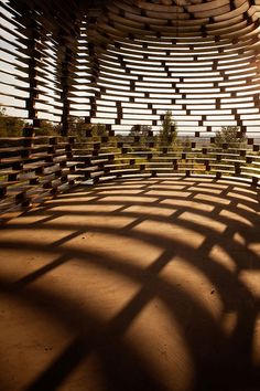 the sun shines through an abstract structure made out of wooden strips and sticks, with shadows on the ground