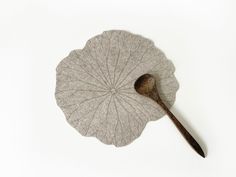 a large leaf with a wooden spoon on it's end sitting on a white surface