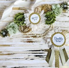 two ribbons and some flowers on top of a wooden table with the words daddy to be