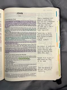 an open bible with the word john written in rainbow colors on it's pages