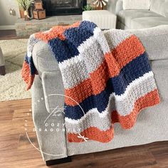 a couch with a crocheted blanket sitting on it's back in front of a fire place