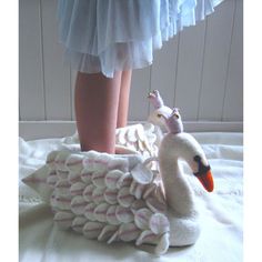 a close up of a person's legs on a bed with a stuffed swan