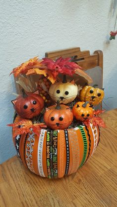 an arrangement of pumpkins and gourds in a bowl on a wooden table