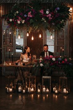 a man and woman sitting at a table with candles