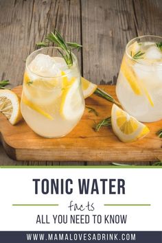 two glasses of tonic water with lemons and rosemary garnish on a cutting board