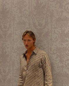 a young man standing in front of a wall