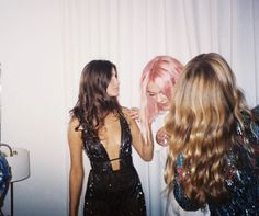 two women standing next to each other in front of a wall with sequins on it