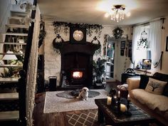 a living room filled with furniture and a fire place next to a stair case covered in plants