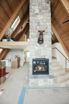 an unfinished room with a fireplace in the middle and a deer head on the wall