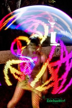 a woman is dancing with colorful lights on her body in the dark and blurry image