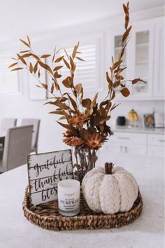 a basket filled with pumpkins sitting on top of a counter next to a candle