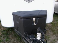 a black cooler sitting next to a white trailer