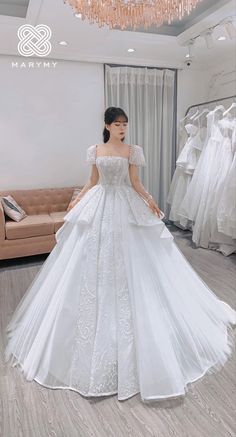 a woman standing in front of a mirror wearing a white wedding dress with ruffled sleeves