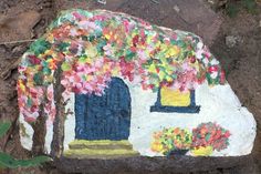 a rock with flowers painted on it sitting in the dirt