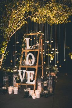 a ladder decorated with flowers and candles stands in front of an arch that says i love