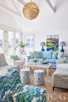 a living room filled with furniture and a chandelier hanging above the couches