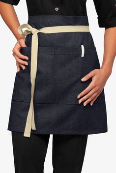 a woman wearing an apron and holding her hands on her hip, with one hand in the pocket